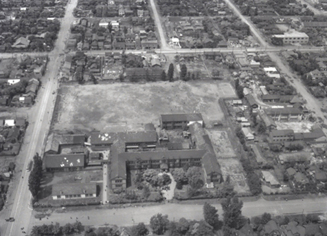 かつて1962年(昭和37)まで北4条西19丁目にあった札幌西高等学校を南から北に向かっての空撮(1957年(昭和33)当時)。現在、西本願寺札幌別院と札幌龍谷学園高校のある場所です。校舎敷地北側の北5条通りと西側の20丁目(市場通り)に市電北5条線が走っているのが見えます。右端の中心あたりに現在のミニ大通17丁目の突端もわずかに見えます。札幌市公文書館所蔵写真