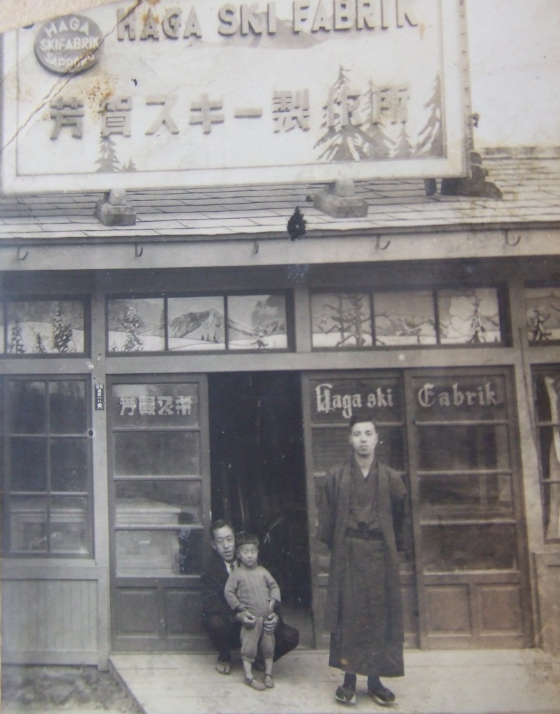 1937年(昭和12)北5条西19丁目にあった芳賀スキー店舗前での写真(芳賀孝郎さん提供) 当時3才の芳賀さんを抱えておられるのが、芳賀スキー製作所社長であられたお父様の芳賀藤左衛門さんです。